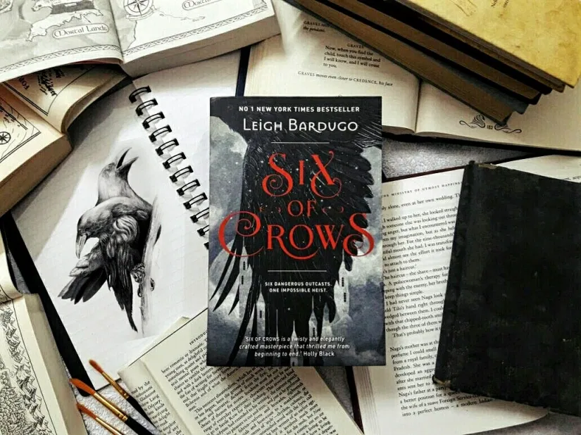 image of the six of crows book beside a drawing of a crow